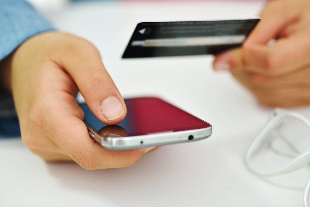 Una mano humana sobre una tableta y una tarjeta de crédito para hacer compras en línea